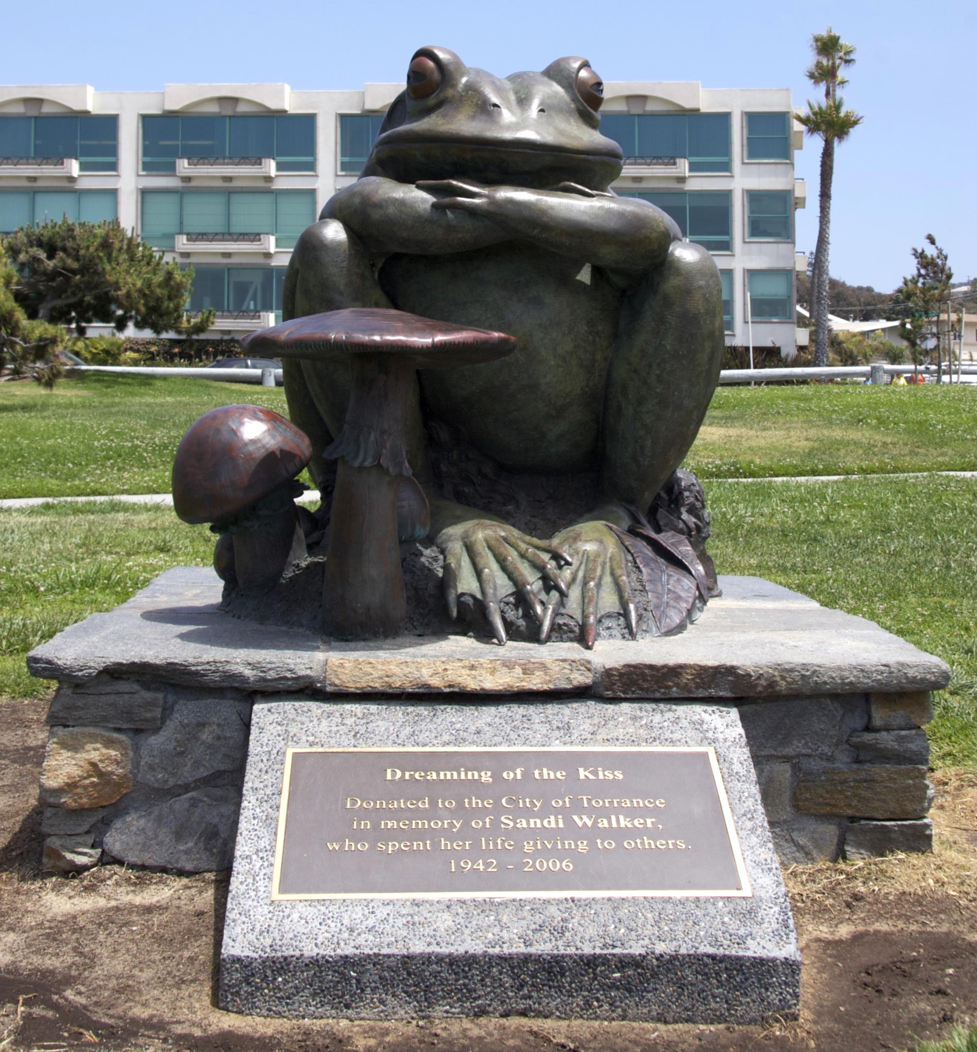 Sculpture at Miramar Park by Kim Kori titled “Dreaming of the Kiss,” featuring a frog with crossed arms.