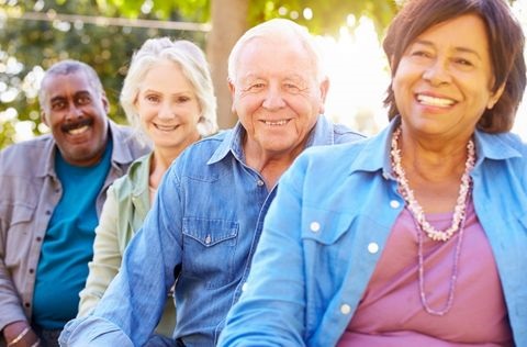 Four senior citizens sitting together, smiling and enjoying each other’s company.