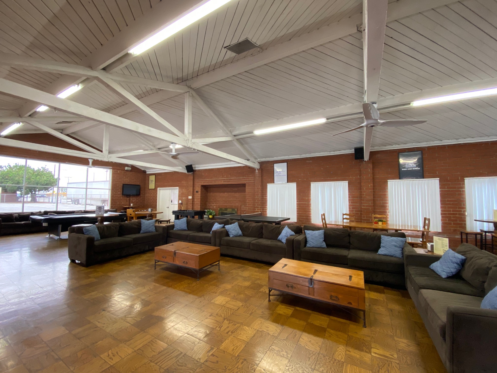 Spacious recreation room featuring multiple sofas, tables, televisions, and a pool table for leisure activities.