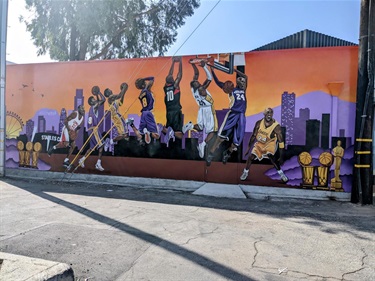 Mural at Burger City Grill featuring Kobe Bryant dunking and wearing uniforms from different parts of his career.