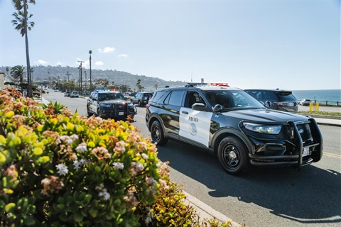 Two police cruisers driving along the beach in Torrance
